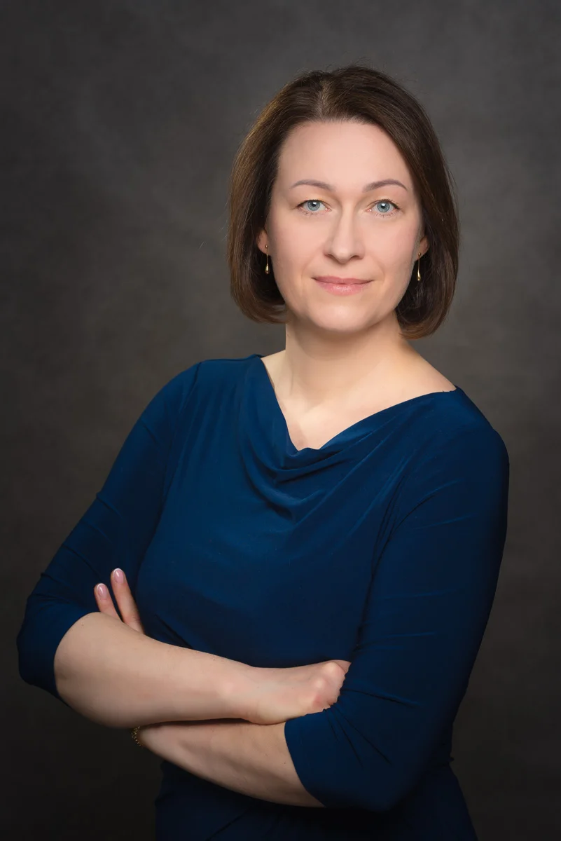 A brown haired woman with a blue dark shirt
