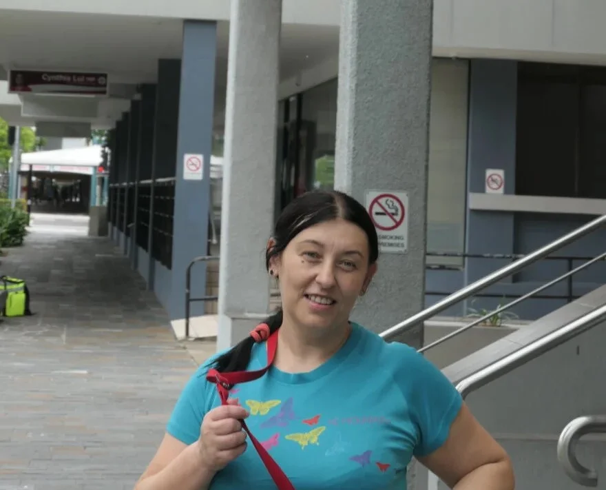 A woman outdoors with a blue shirt and dark hair