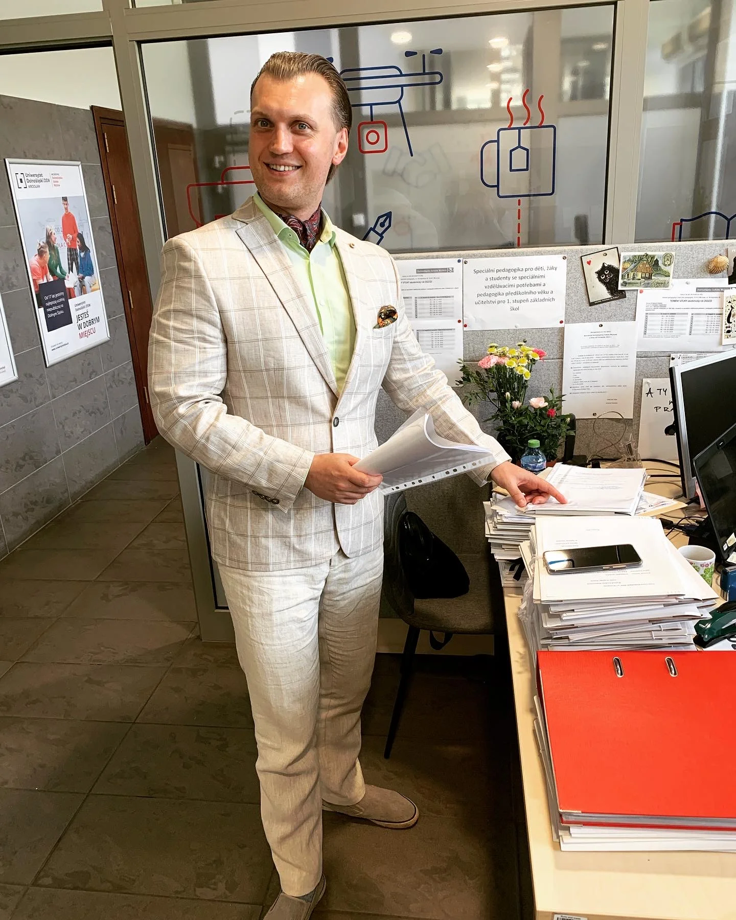 Man in white suit, standing in an office