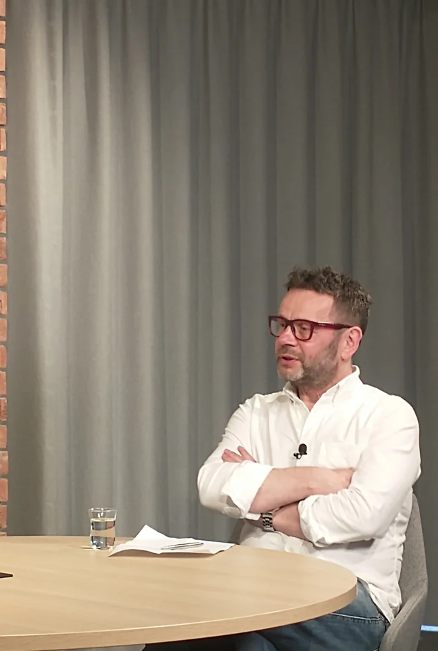 Man with glasses and a white shirt sitting at a table
