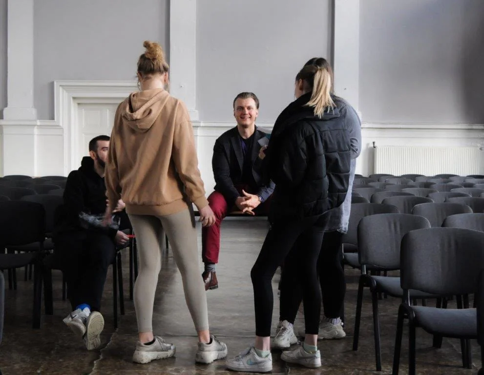 five people standing and sitting in a circle