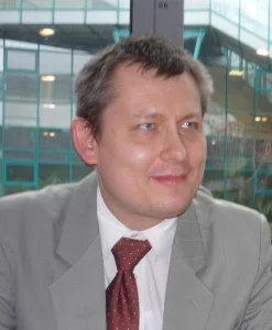 A man with dark hair in a grey blazer