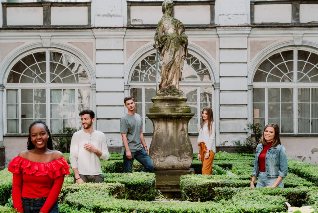 Five people standing in front of a statue and a building